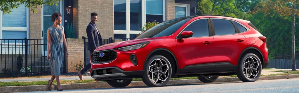 Red SUV parked outside a modern townhouse with a couple walking nearby