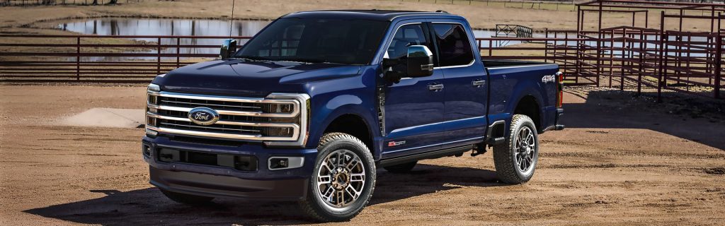 2026 Ford Super Duty truck in blue, parked in a rural setting with a 4x4 badge.