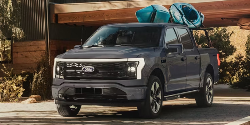 Gray Ford F-150 pickup truck parked in front of a wooden building with kayaks secured on the roof rack