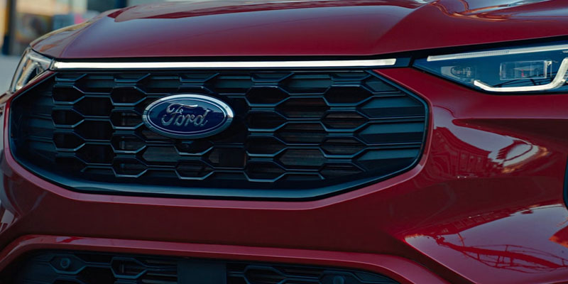 Close-up view of the front grille and headlight of a red Ford vehicle showing the Ford emblem